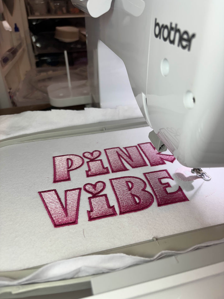 Embroidery machine with 'Pink Vibe' design on a Brother machine.