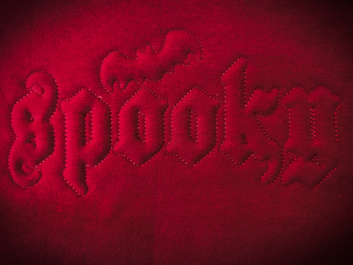Embroidered text on a red fabric background using Spooky Embossed font.
