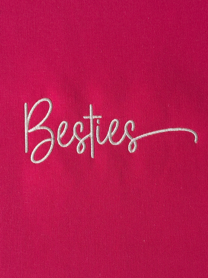 Embroidered word 'Besties' on a pink fabric background